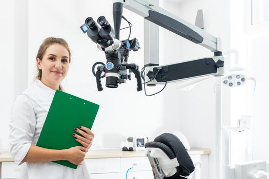 Smiling female dentist holding a clipboard with patient records in hands at dental clinic