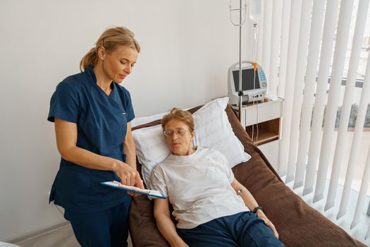 Nurse in uniform explain to patient results of analysis standing in hospital ward in clinic