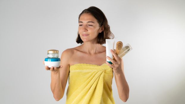 Jars with creams, tubes with cosmetics, massage brush in the hands of a woman after a shower. High quality photo
