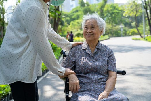 Caregiver help and care Asian senior or elderly old lady woman patient sitting on wheelchair in park, healthy strong medical concept.