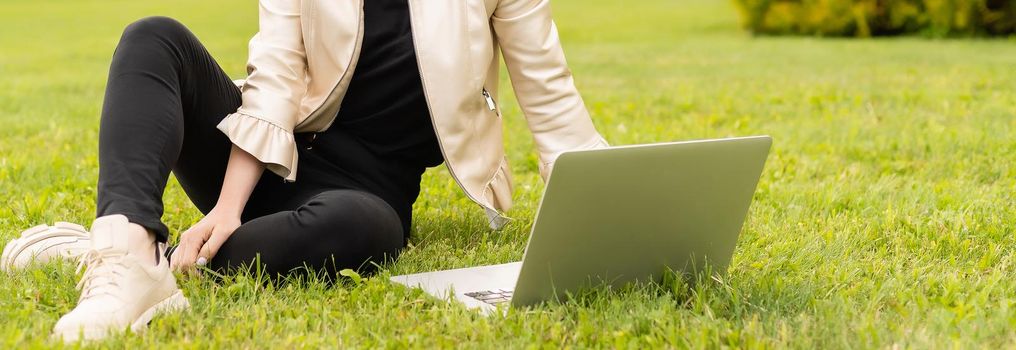 Female copywriter working on laptop in the park, view over the shoulder.