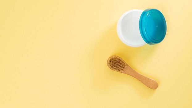 Cream jar and massage brush on a yellow background with text space. High quality photo