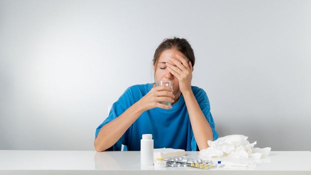 A woman is sick - she drinks water with lemon, pills and a thermometer are on the table. High quality photo