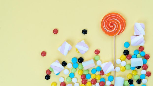 Mix of sweets - lollipop, sweets, marshmallows on a yellow background with a place under the text. High quality photo