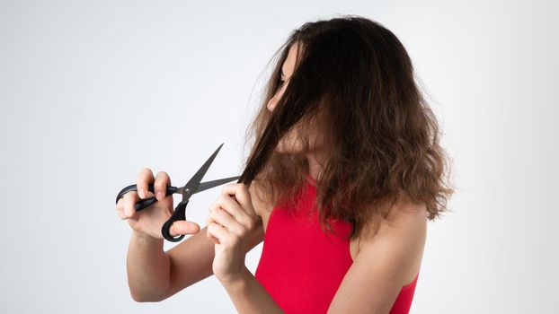 A woman with scissors cuts off the split ends of naughty, unhealthy hair. High quality photo