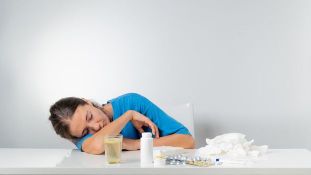 A sick woman without strength lies on the table next to the pills. High quality photo