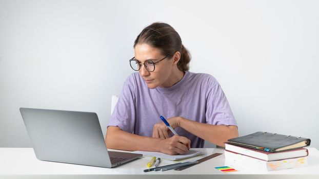 A woman sits at a laptop with notebooks, books - remote work, online learning. High quality photo