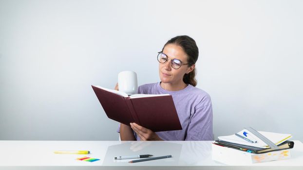 A girl reads a book or textbook and drinks coffee - study, homework. High quality photo