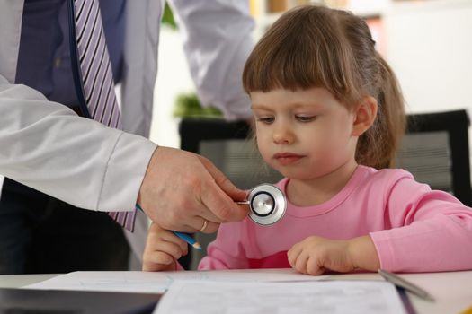 Hands of pediatrician doctor examining small child with stethoscope. Pediatrics and medicine healthcare concept