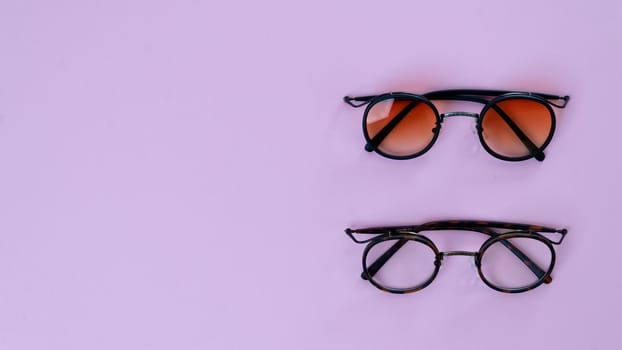 Eyeglasses and sunglasses on a purple background with space for text. High quality photo