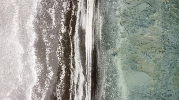 Background screensaver shore with white and black sand and clear blue water with quadcopter