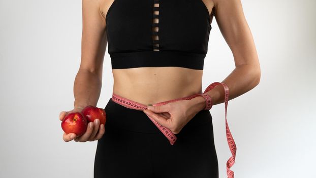 Weight loss, nutrition and sports - a woman with fruits measures her waist. High quality photo