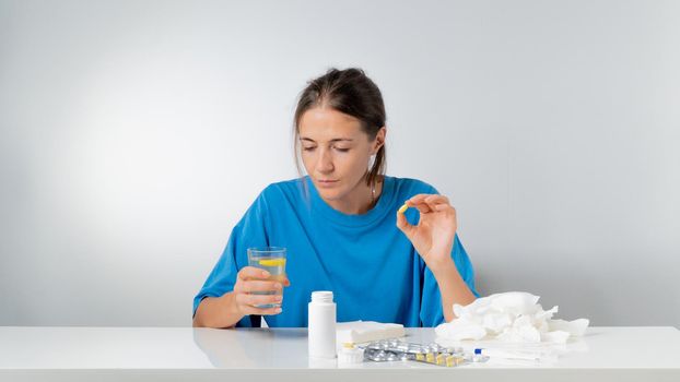 Woman with a pill in her hand and a glass of water - treatment for colds and flu. High quality photo