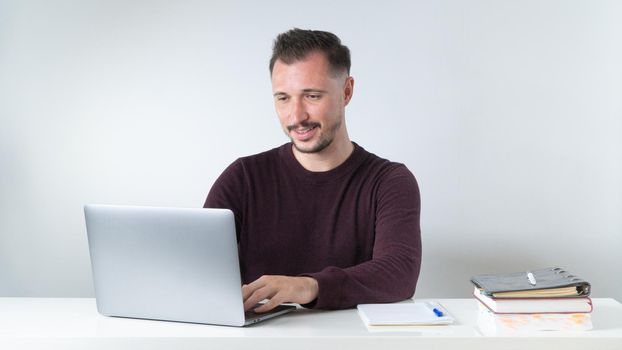 A man types in a laptop at a desk in the office or at a remote work. High quality photo