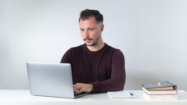 Concentrated work, a man works at a laptop at an office desk. High quality photo