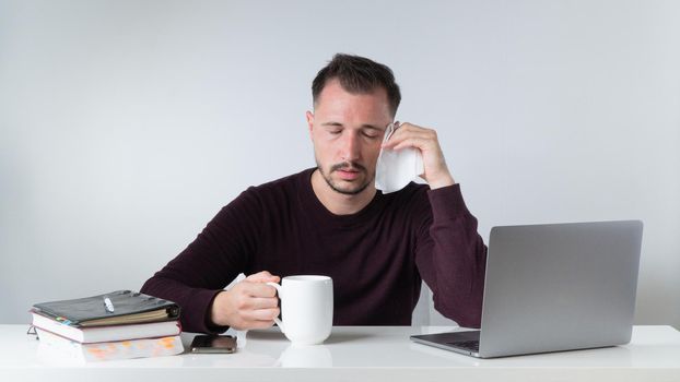 Sick in the workplace - a man with a runny nose and headache in the office. High quality photo