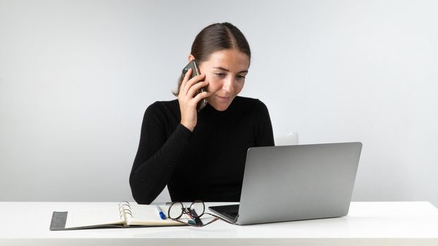 A woman works in an office with a telephone and a computer. High quality photo