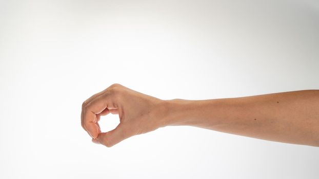 Hand woman gesture fingers clenched into a ring holding a cylindrical object. High quality photo