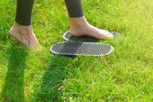 feet of a woman standing on a sadhu yoga board with nails outdoors. Close up. Copy space