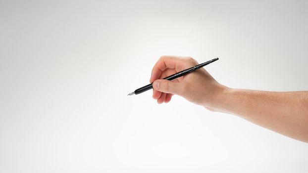 The right hand of a man holds a pen for calligraphy and writing, gesture writes. High quality photo