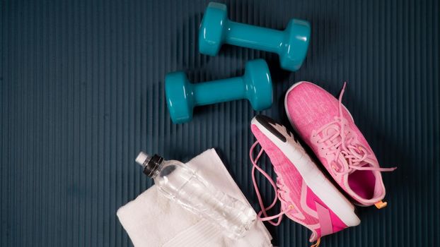 Workout kit - sneakers, bottle of water, towel and dumbbells on the sports mat. High quality photo