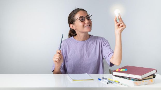A girl is learning, a light bulb in her hand - an idea came. High quality photo