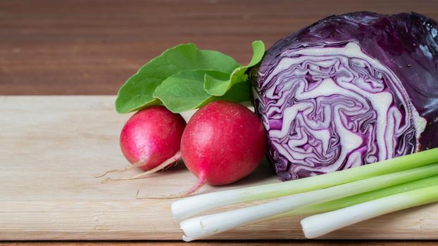 Radishes, kolbari cabbage and green onions on a wooden board close-up. High quality photo