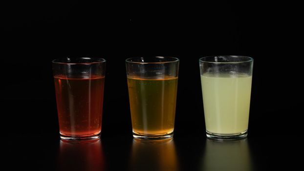 Three glasses of colored water, drinks, juices and cocktails on a black background. High quality photo