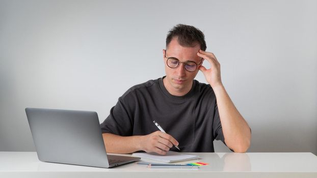 A focused male student writes in a notebook - work and study. High quality photo