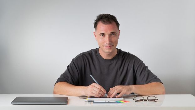 The guy at the desk makes notes in a notebook - study and work. High quality photo