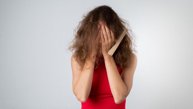 The woman covered her face with her hands - stress due to naughty, brittle and tangled hair. High quality photo