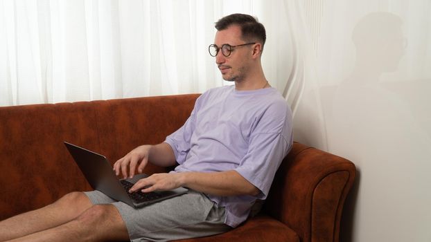 A guy with a laptop on the couch, remote work and study. High quality photo