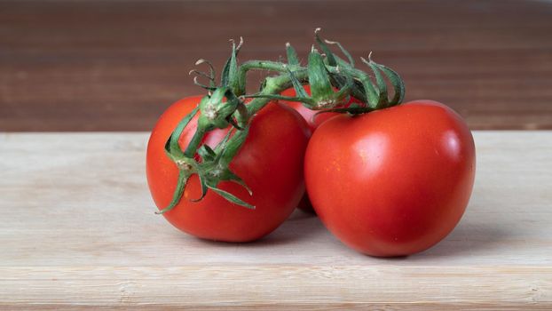 tomatoes on a branch on a wooden board close-up background. High quality photo