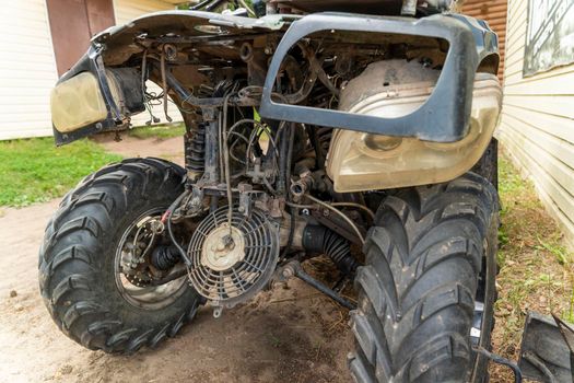 the front part of a broken and disassembled ATV in need of repair. cooling radiator, cooling fan