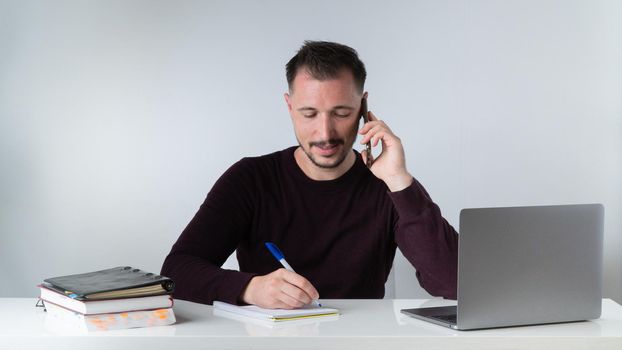 A man works in an office with a laptop, documents and talks on the phone. High quality photo