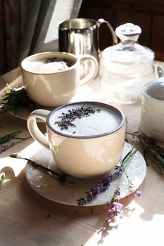 A cup of home made earl grey tea latte drink with lavanda flower buds in white cups with fresh lavanda flowers on white table, good morning concept, selective focus.