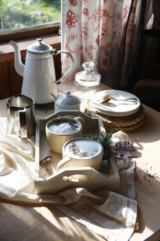 Morning in rustic kitchen with home made earl grey tea latte drink with lavanda flower buds in white cups with fresh lavanda flowers on white table, good morning concept, selective focus.