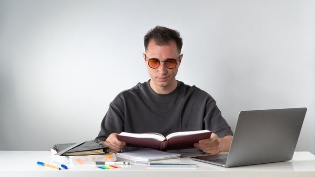 Student with a textbook at a desk on a white background. High quality photo