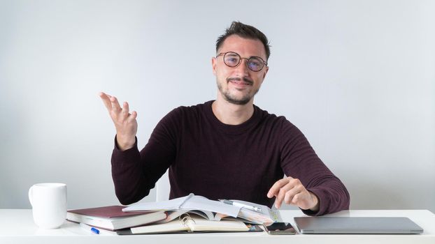 An employee with glasses in the office at a desk with a laptop. High quality photo