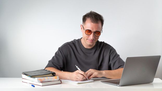 Home Online Education - Male Student with Laptop and Notebook. High quality photo