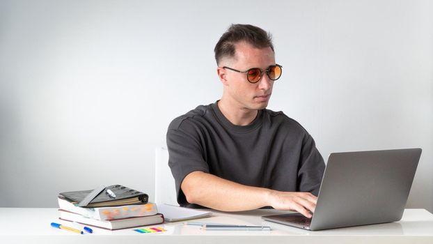 Male student typing on laptop at desk. High quality photo