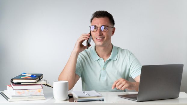 A student guy talking on the phone at his desk. High quality photo