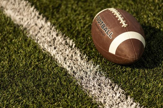 American football ball on the grass of a stadium.