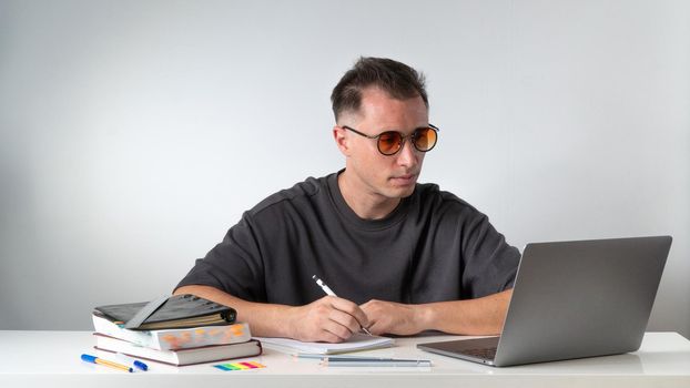 Online learning at the desk in front of the computer - a guy student. High quality photo