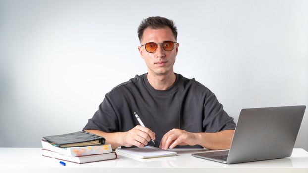 A student with glasses writes in a notebook - education and work. High quality photo