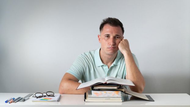 Bored student sits at textbooks and notebooks - study. High quality photo