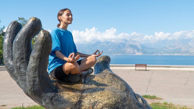 A woman meditates against the backdrop of the sea and mountains. High quality photo