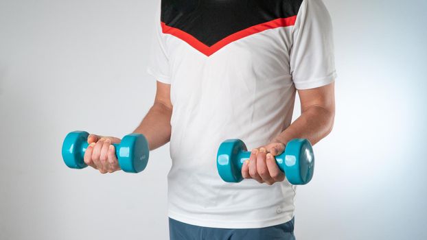 A sporty man with dumbbells in his hands does a workout to pump the muscles of the hands. High quality photo