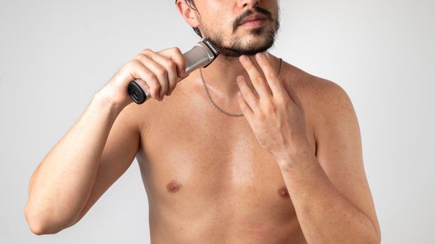 Shaving and styling a beard and mustache, a bearded guy with a razor in his hand. High quality photo