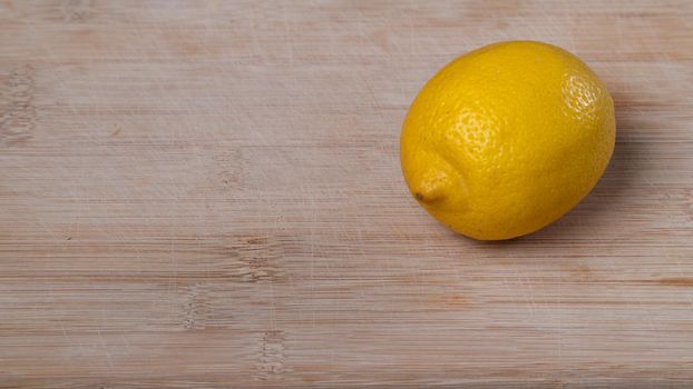 One lemon on a wooden background with space for text. High quality photo